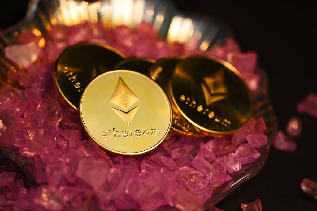 two gold coin sitting on top of a pile of pink crystals